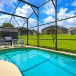 A screened-in backyard pool in a Florida home with lounge chairs and a barbecue grill.