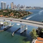 A scenic view of Miami Beach with high-rise buildings, waterfront homes, and a bridge, showcasing Florida’s appeal for foreign homebuyers.