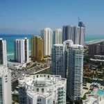 Aerial view of beachfront high-rise condos and suburban homes in Florida, showcasing the contrast between urban and residential real estate options.