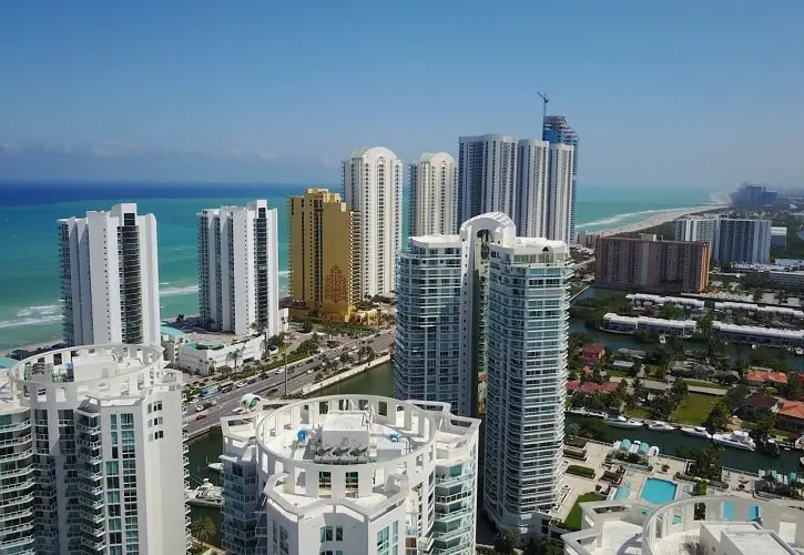 Aerial view of beachfront high-rise condos and suburban homes in Florida, showcasing the contrast between urban and residential real estate options.