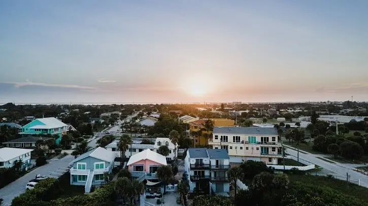 Aerial view of a coastal neighborhood in Florida at sunset, featuring colorful homes and palm trees.