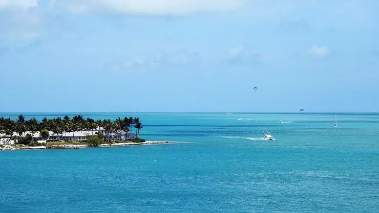 A scenic ocean view of Key West, Florida, featuring waterfront homes, palm trees, and boats on the turquoise waters.
