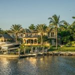 Luxury waterfront home with a private dock and palm trees in Naples, Florida.