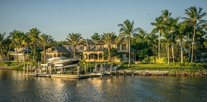 Luxury waterfront home with a private dock and palm trees in Naples, Florida.